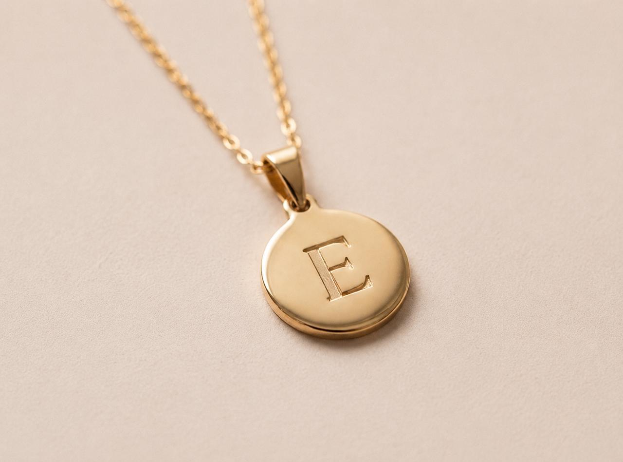 A piece of jewelry engraved with a retailer's logo, photographed on a stone surface.