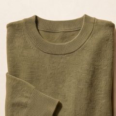 A folded knit garment on a stone surface