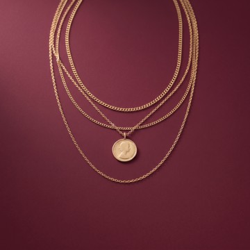 Layered gold necklaces on a plum background