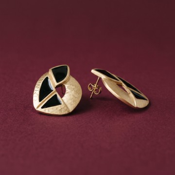 Gold and black statement earrings on a plum background