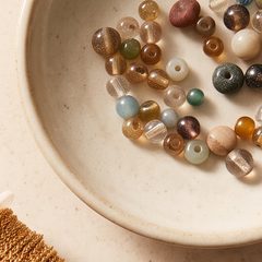 A shallow ceramic dish of mixed glass and stone beads