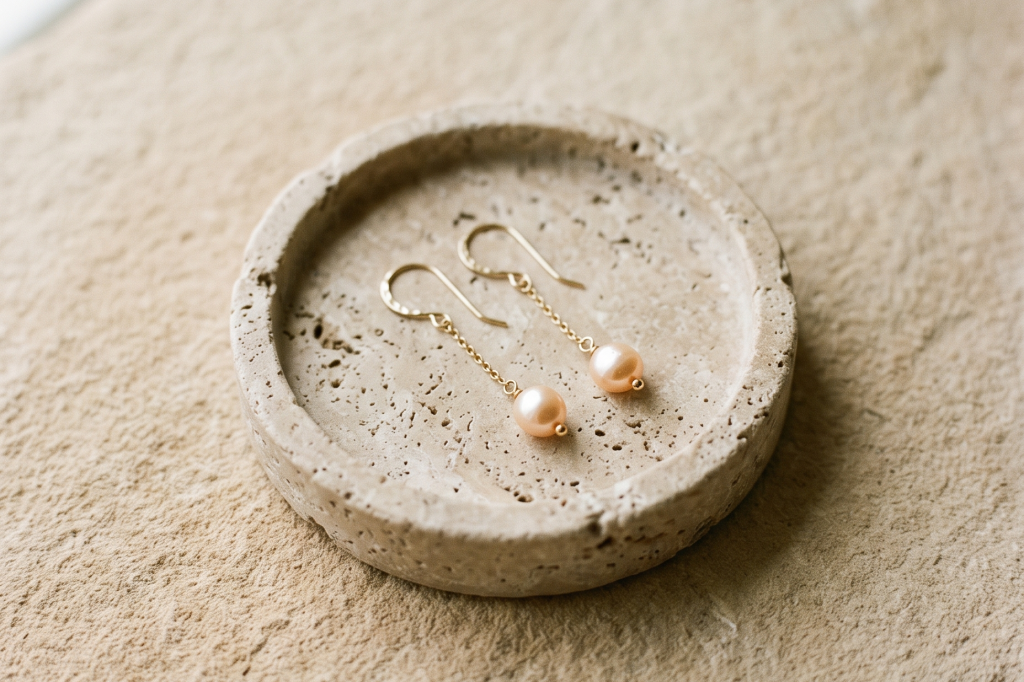 Gold earrings arranged on a burgundy surface, overhead editorial still life